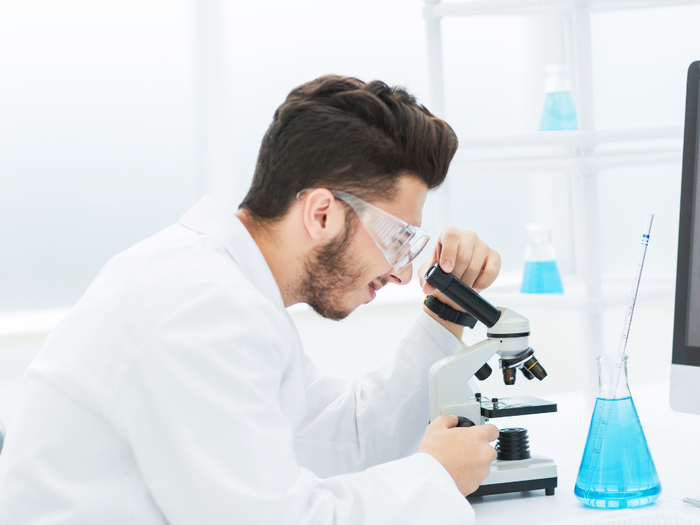Scientist examining samples under microscope.